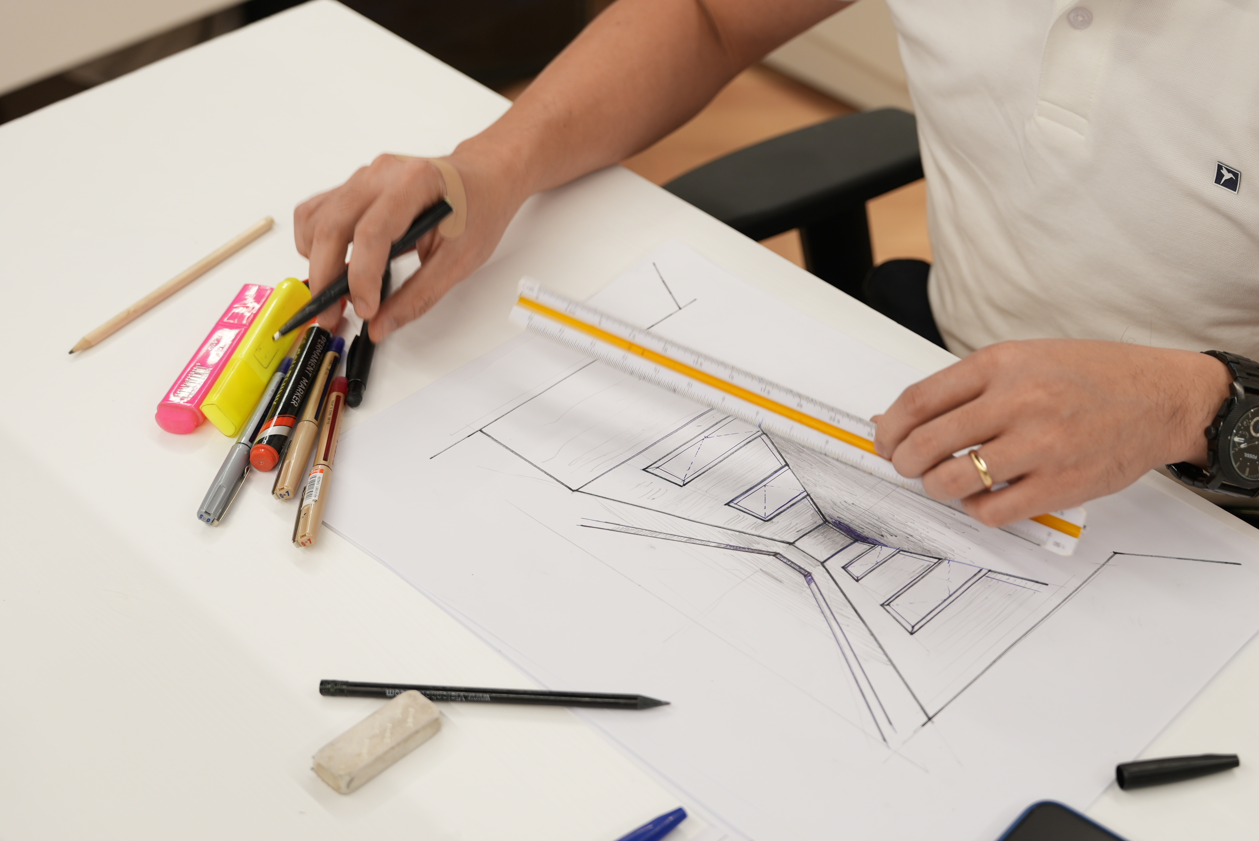 Blueline designer hand-sketching an interior layout with rulers and markers