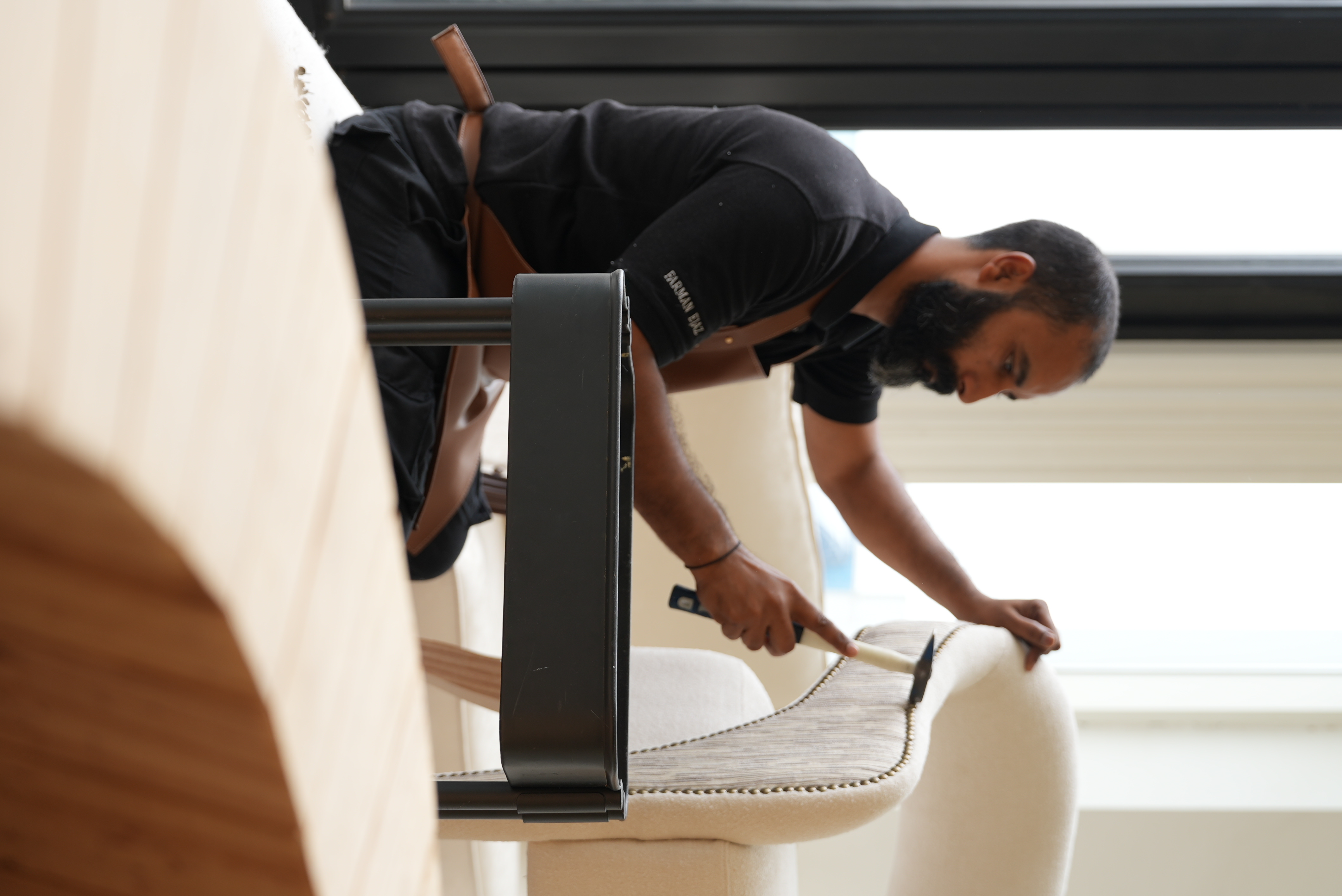 Craftsman nailing upholstery fabric to a dining chair